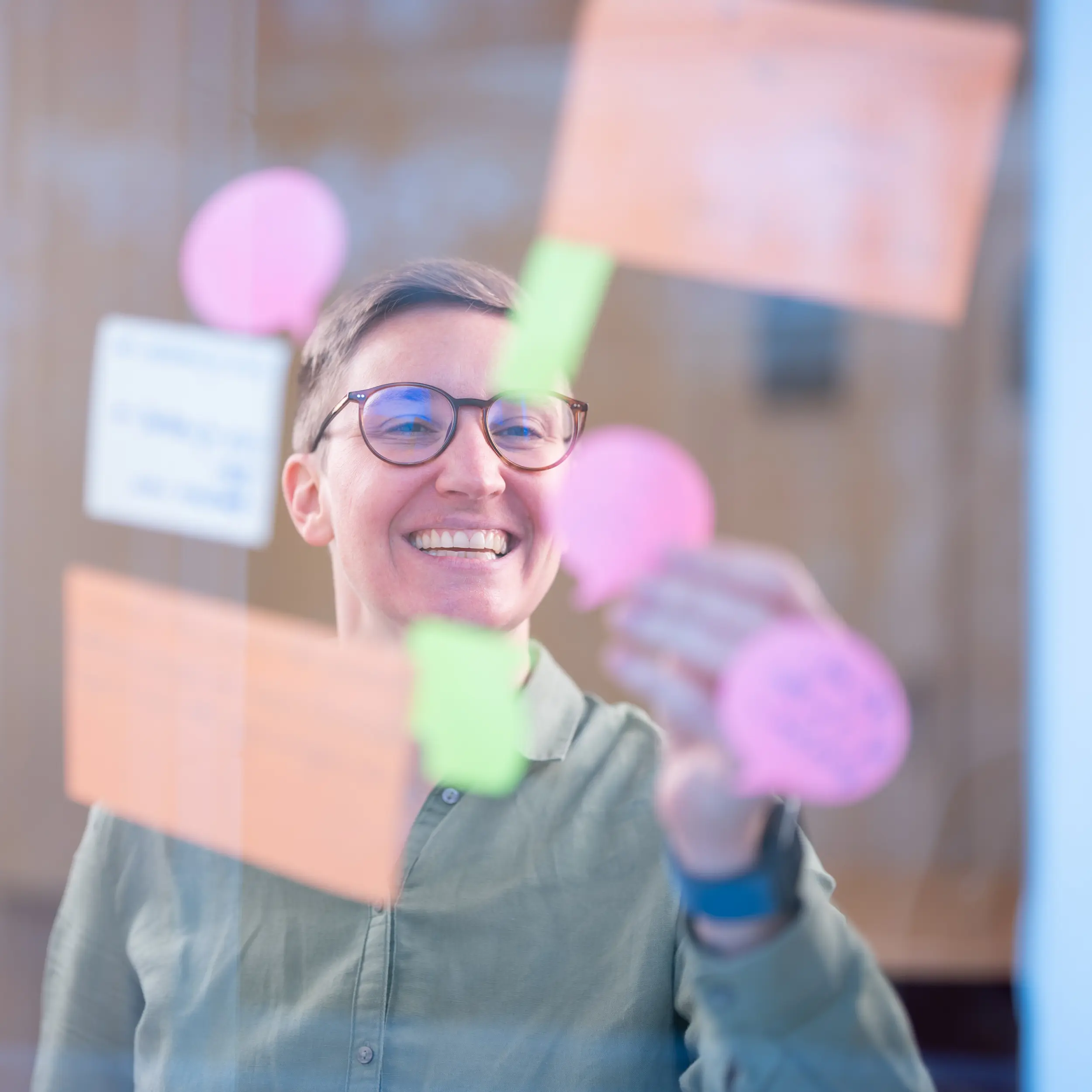 Frau klebt Post-it an Glaswand während eines Karriereberatungs-Workshops bei OMC Berlin