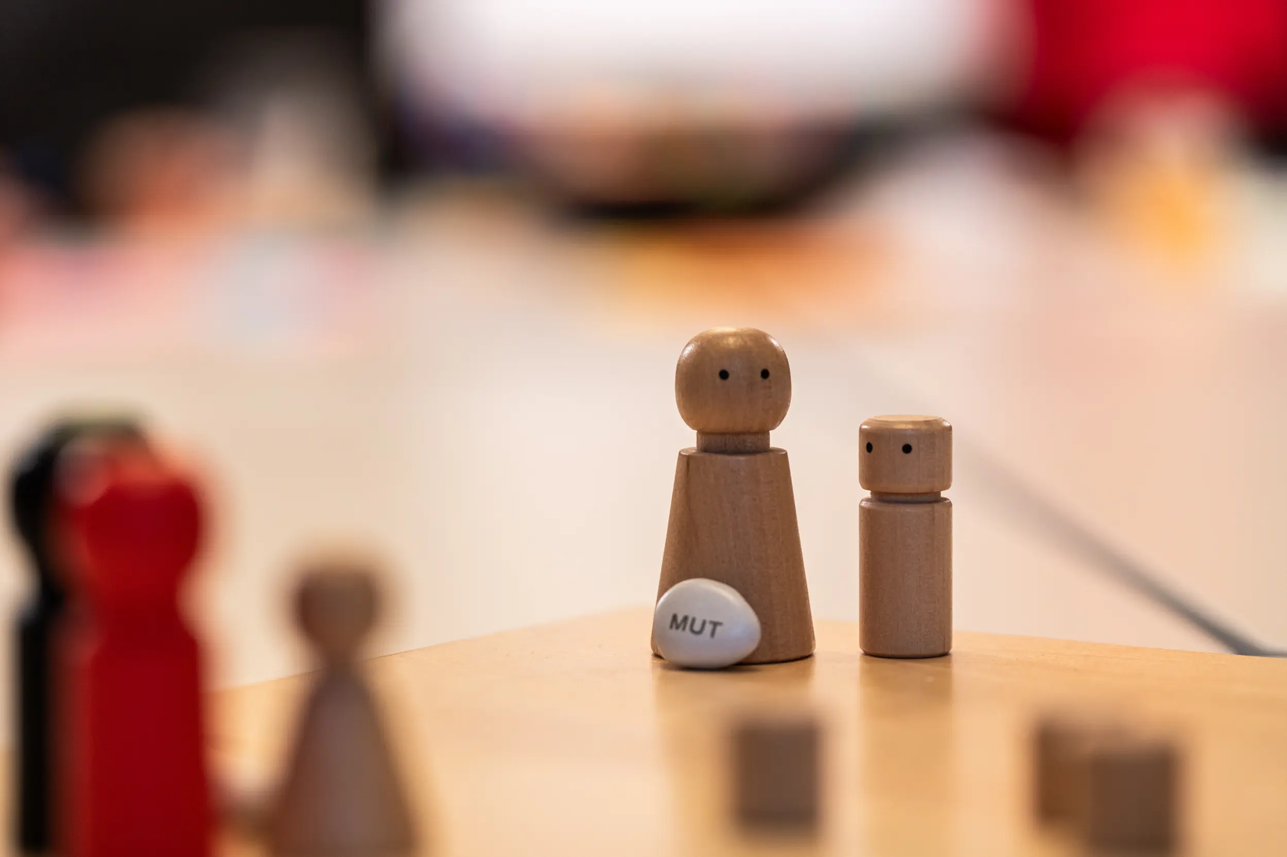 Holzfiguren mit Mutstein als Symbol für Neuanfang und Outplacement-Beratung bei OMC Berlin