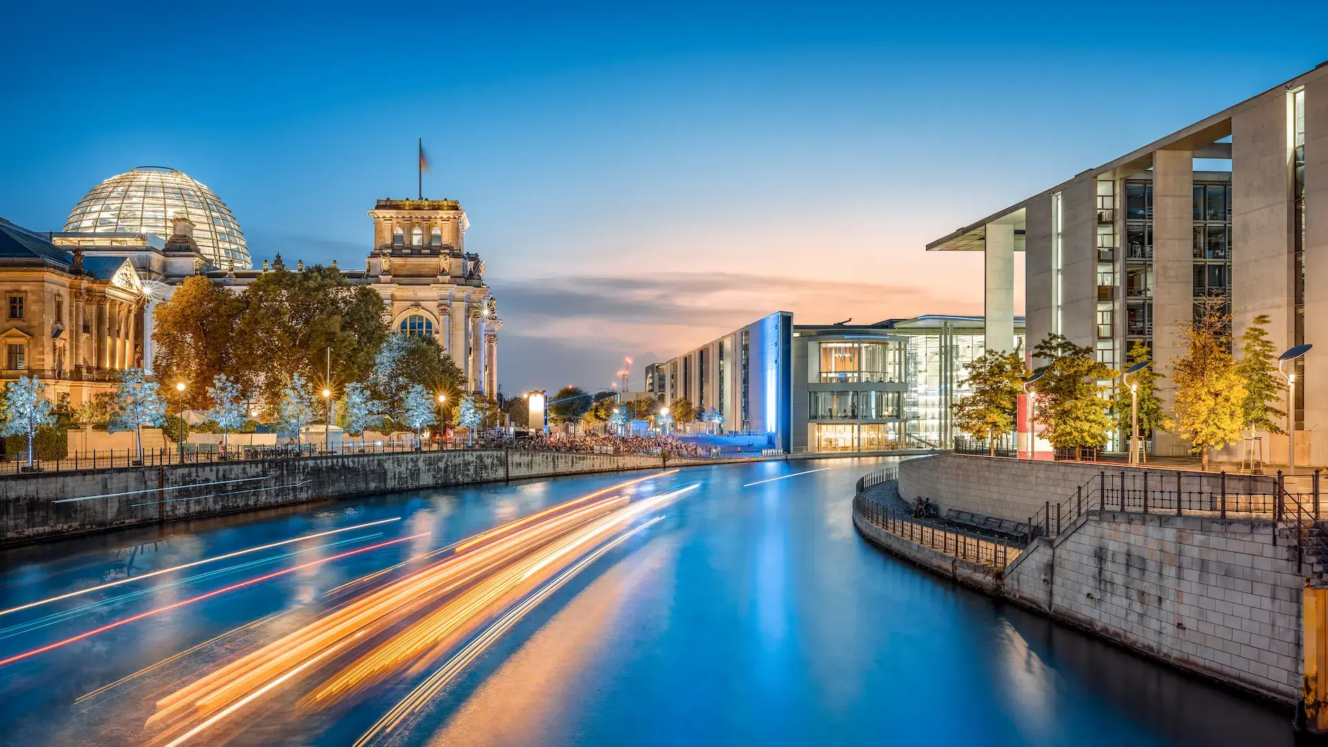 Blick auf das Berliner Regierungsviertel bei Abenddämmerung – beleuchteter Reichstag mit Glaskuppel an der Spree, Sitz politischer Entscheidungsträger im Herzen der Hauptstadt