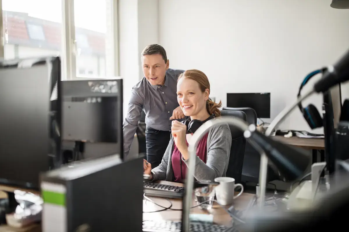 Zwei OMC-Kollegen arbeiten gemeinsam am Bildschirm – engagierter Austausch am Arbeitsplatz in hellem Büro